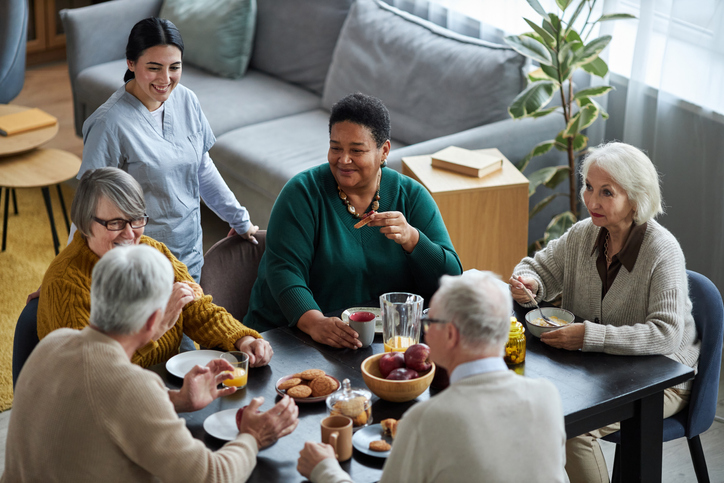 Senior people sitting at table together and smiling happily in retirement home